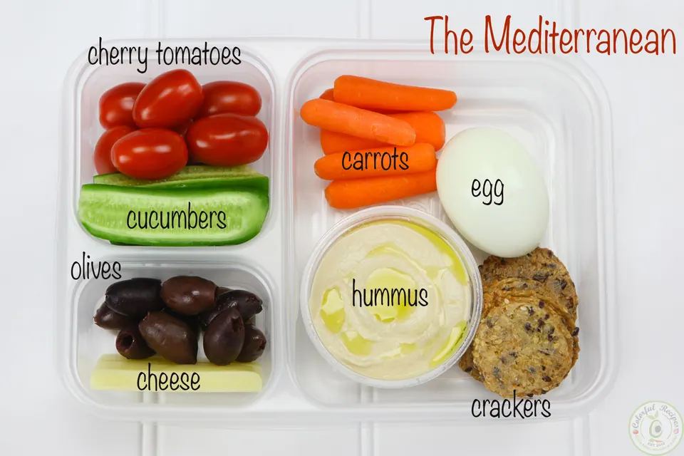 The Mediterranean protein bento box with hummus, egg, crackers, carrots, cucumbers, tomatoes, olives and cheese