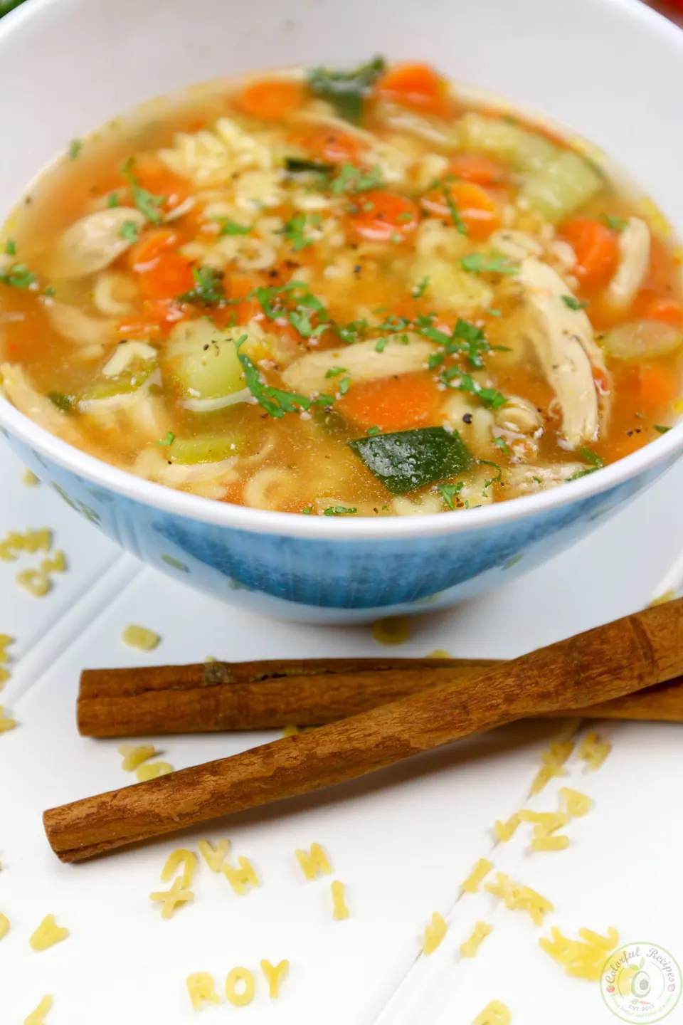 Bowl of alphabet chicken soup with cinnamon sticks and pasta letters spelling Roy