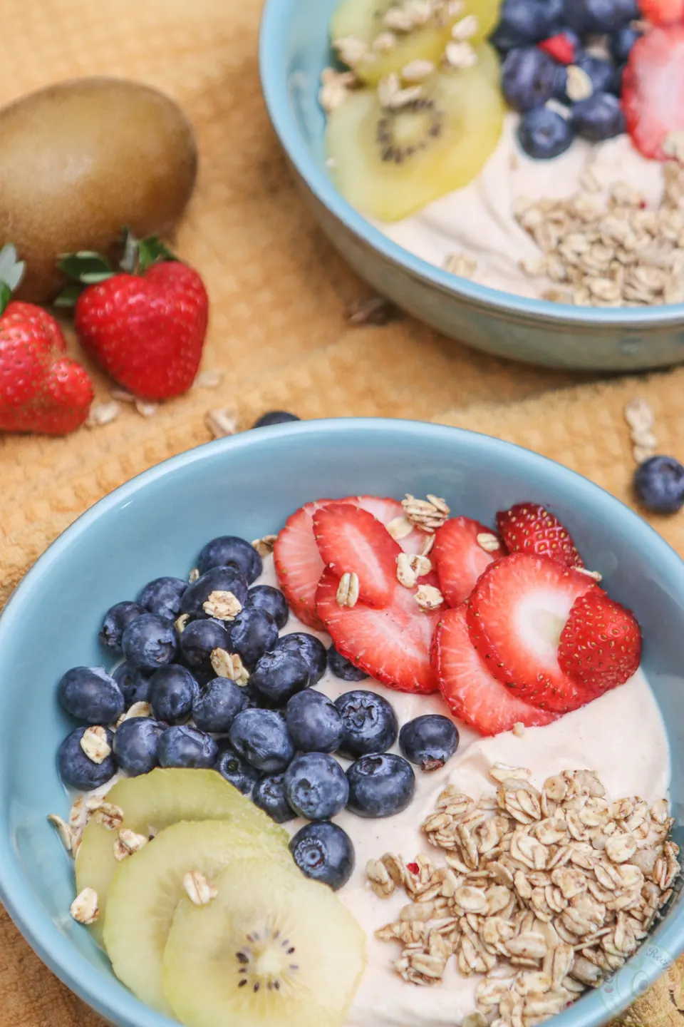 Chinese gooseberry pumpkin breakfast bowl topped with golden kiwi, strawberries, blueberries and granola