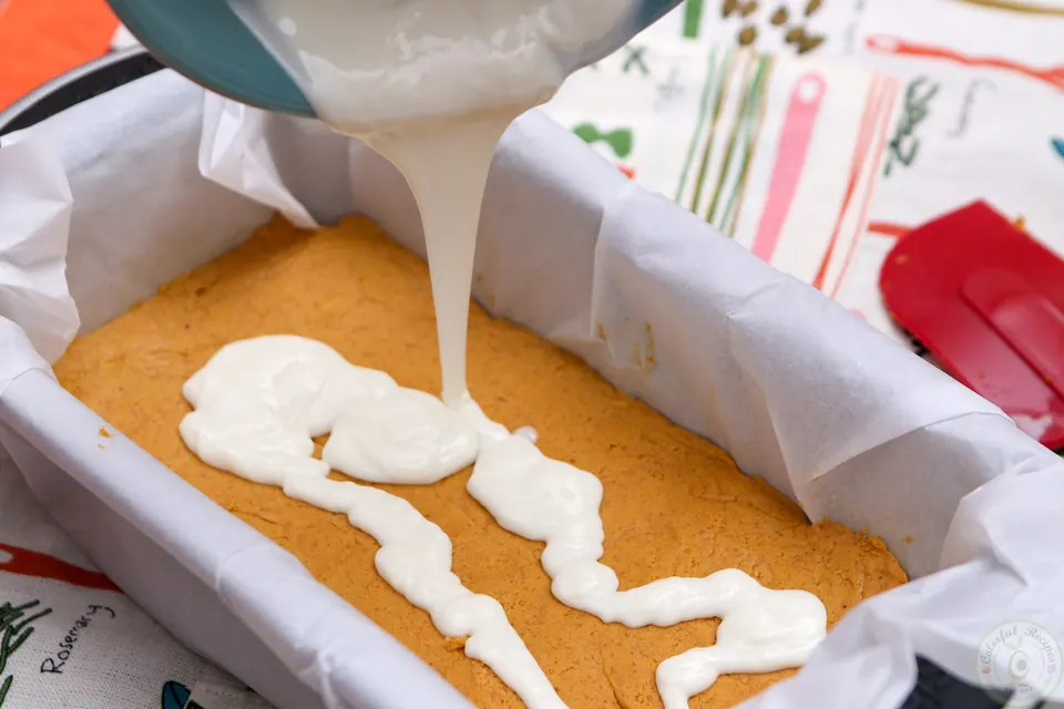 White chocolate spread over pumpkin cheesecake layer in a loaf pan