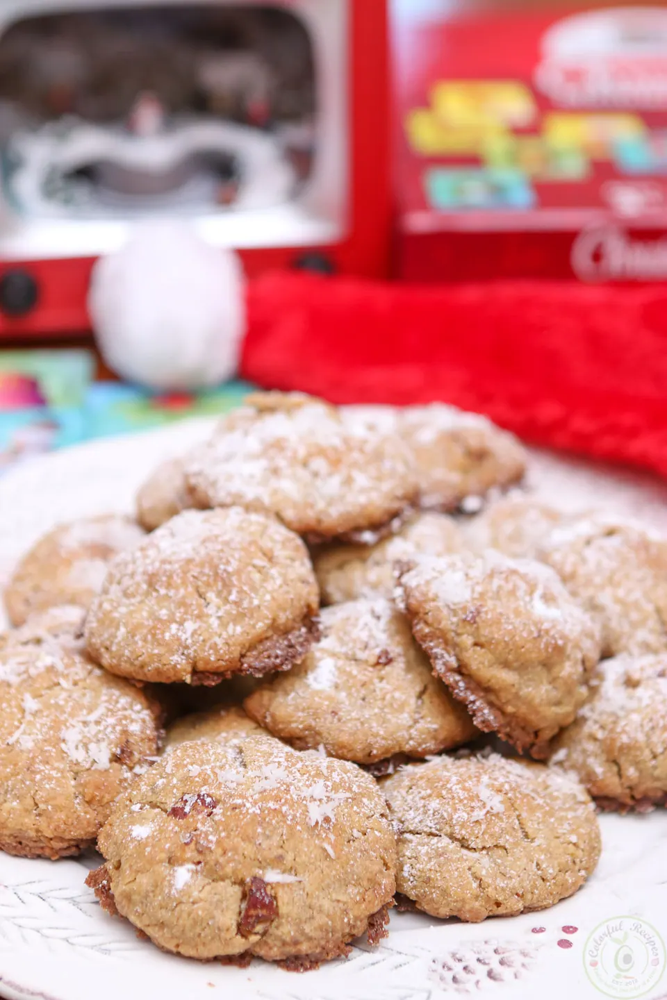 Gluten-free coconut pecan cookies dusted with powdered sugar in front of Christmas decorations