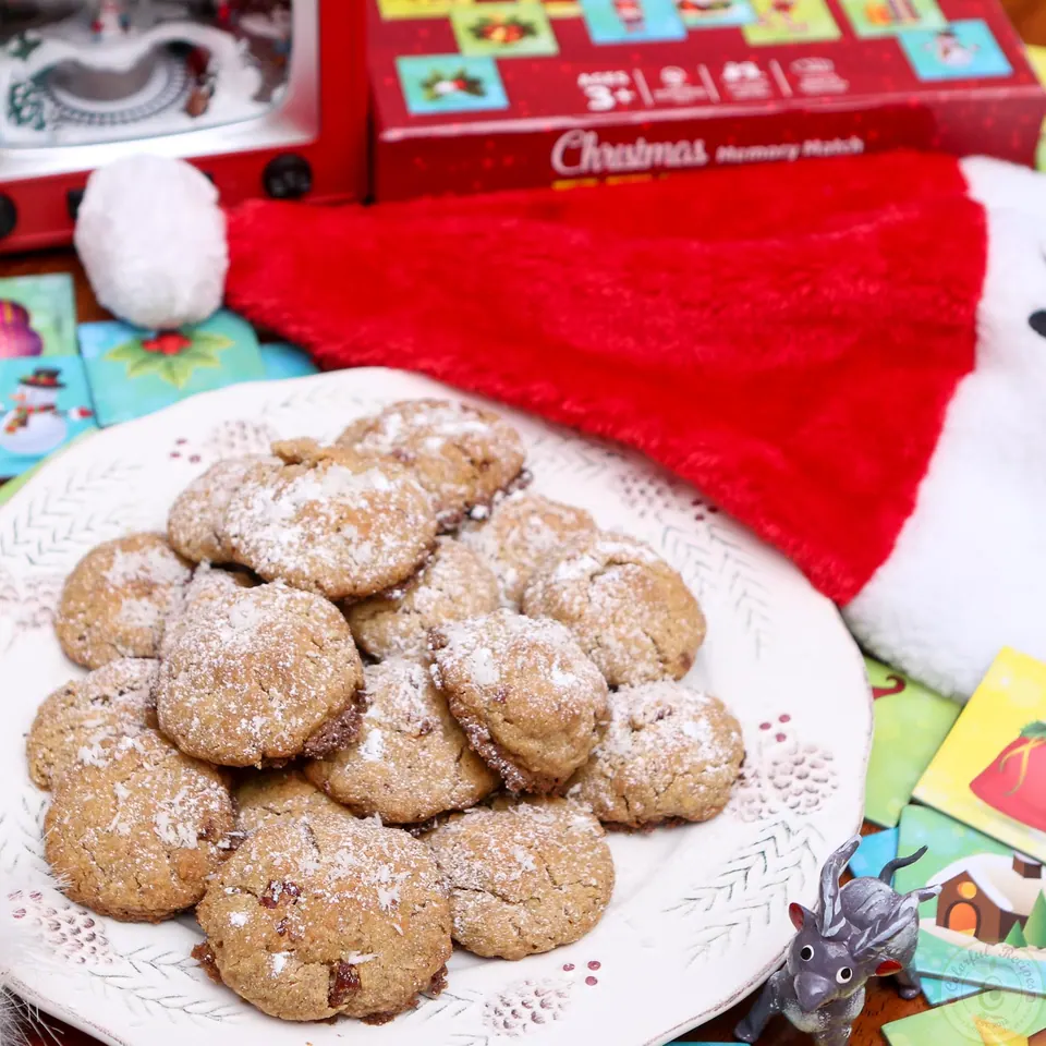 Gluten-free coconut pecan cookies piled on a white plate with holiday decorations