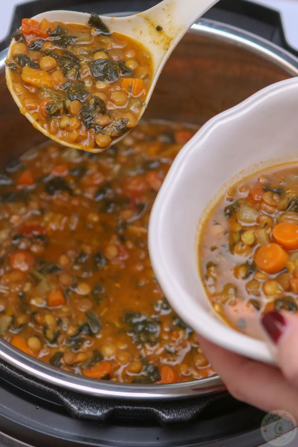 Ladling Instant Pot lentil spinach soup into a white bowl