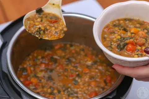 Bowl of Instant Pot lentil spinach hearty soup with carrots and tomatoes