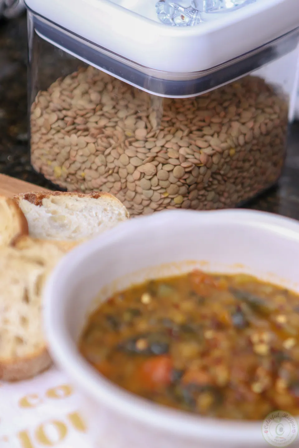 Jar of green lentils behind a bowl of lentil spinach hearty soup