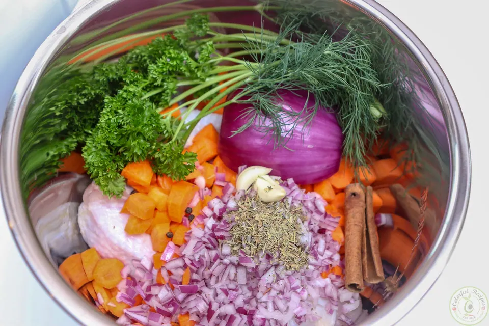 Chicken drumsticks, carrots, red onion, herbs and cinnamon sticks in the Instant Pot for chicken soup