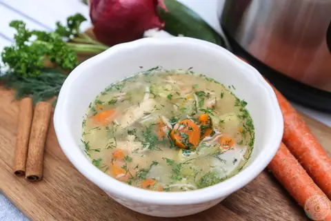 Bowl of Instant Pot chicken soup from scratch with carrots, chicken and fresh herbs