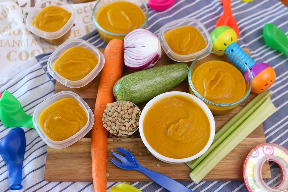 Veggie lentil baby purée in bowls and containers with colorful balloons
