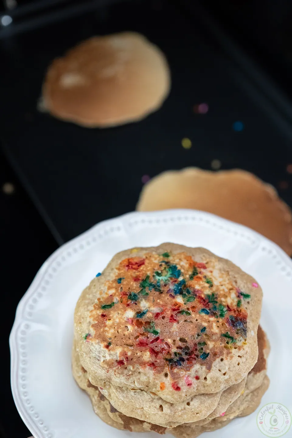 Stack of oatmeal pancakes with sprinkles next to the griddle