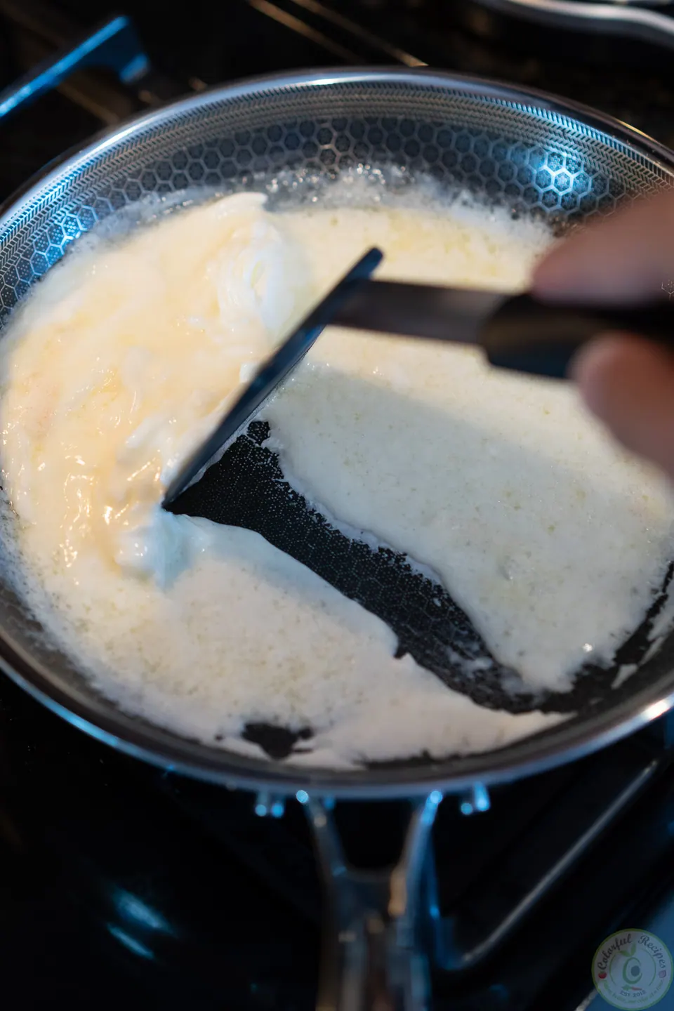 Scraping cooked egg whites to the side of the pan with a spatula