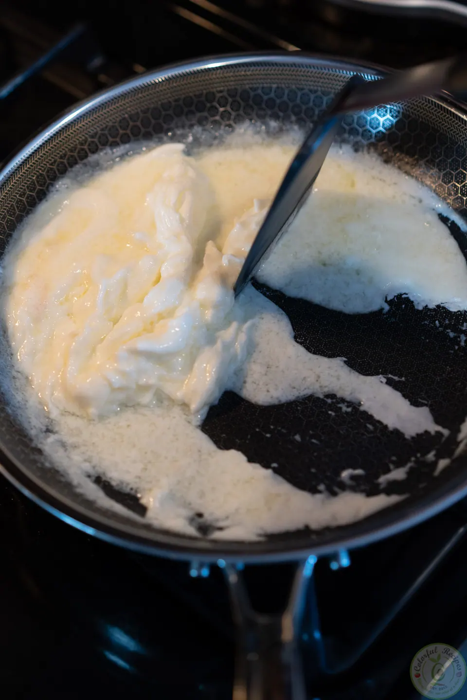 Tilting the pan so the liquid egg whites flow to the center