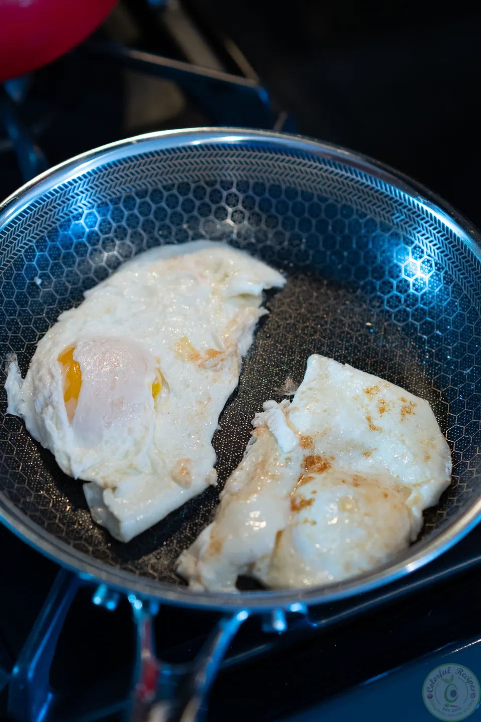 Two eggs frying over medium in a pan