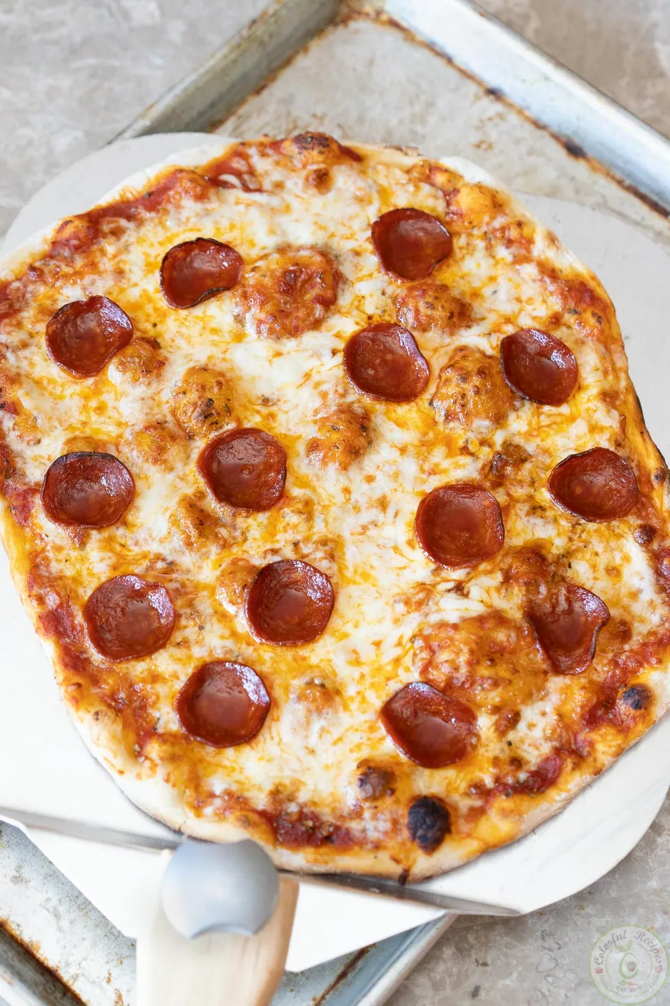 Grilled classic pepperoni pizza on a pizza peel