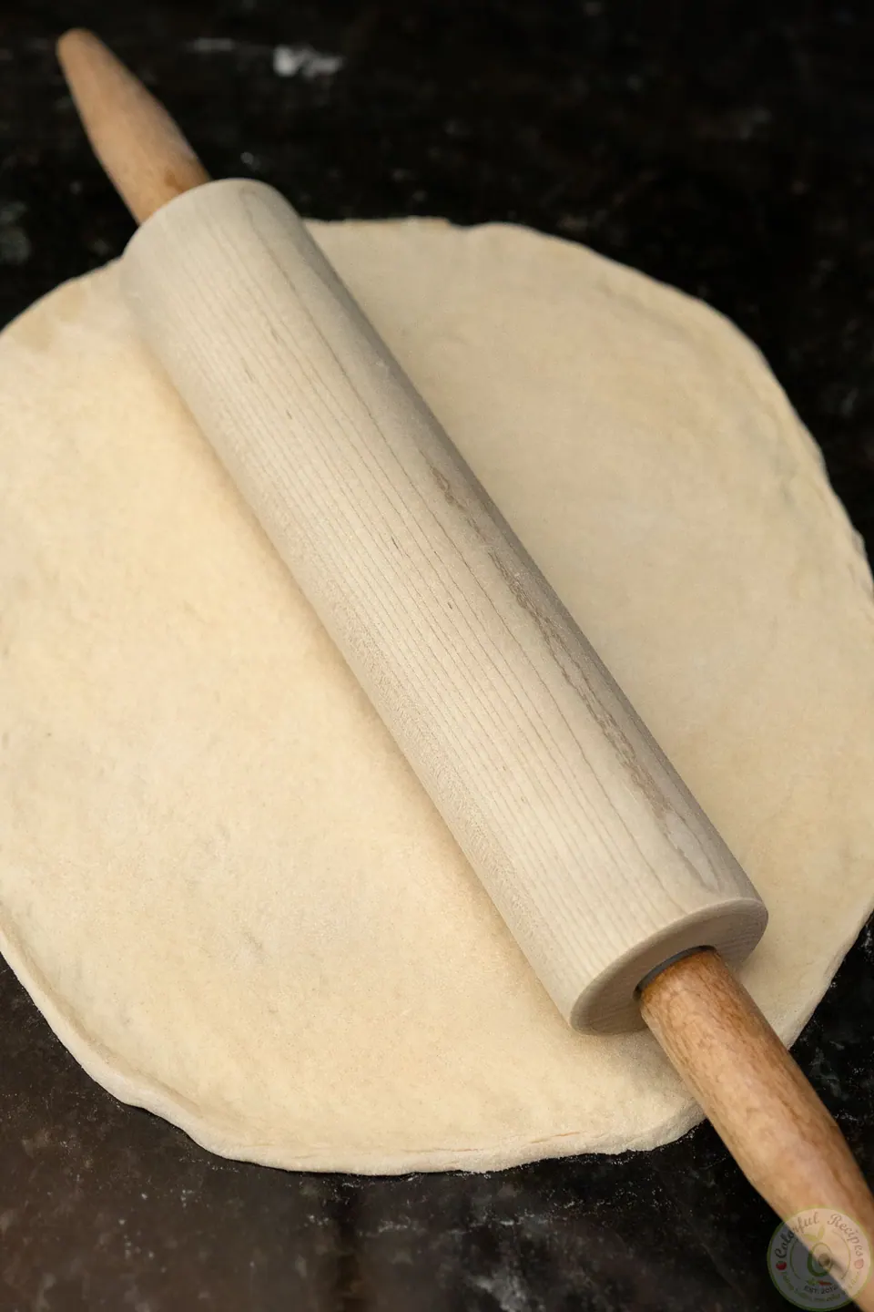 Rolling pizza dough into a 12-inch circle with a rolling pin