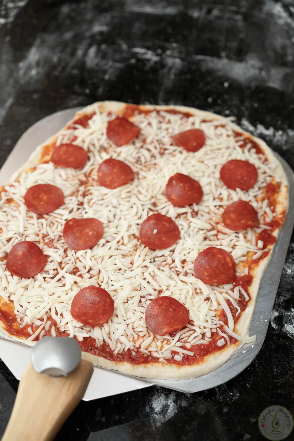 Unbaked pepperoni pizza on a pizza peel ready for the grill
