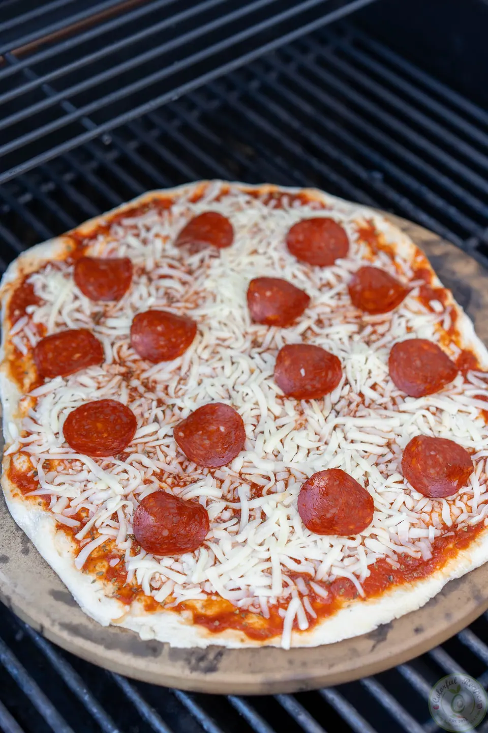 Pepperoni pizza on a hot pizza stone in the grill