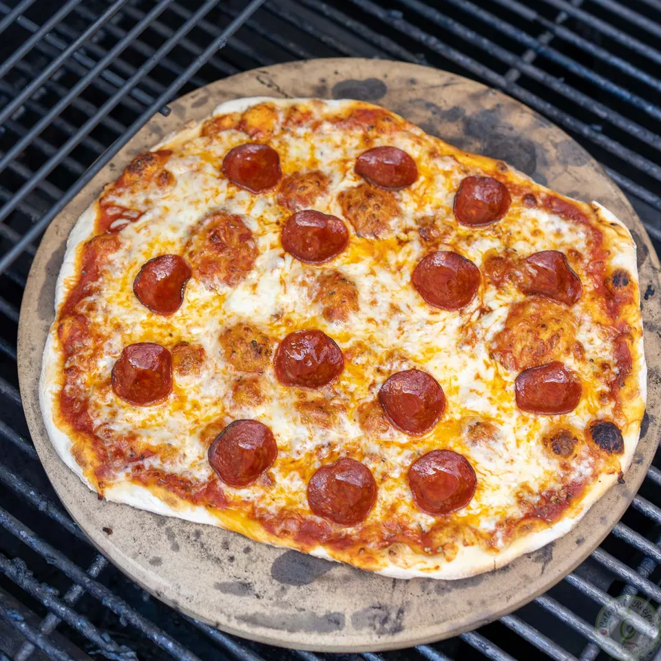 Classic pepperoni pizza baked on a pizza stone on the grill