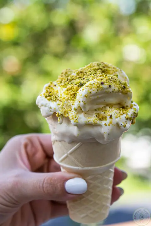 Hand holding a cone of Lebanese milk ice cream booza with crushed pistachios