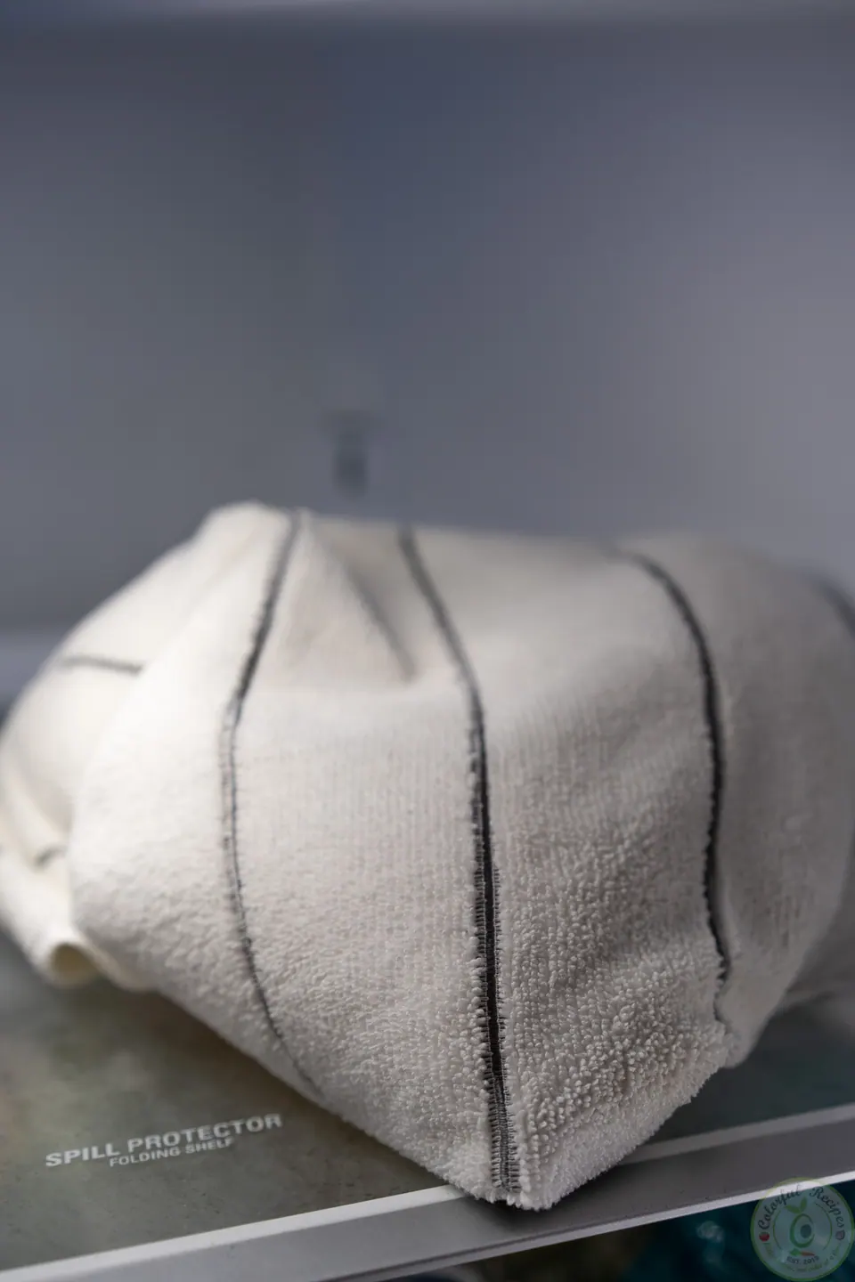 Wrapped pizza dough covered in a towel in the fridge
