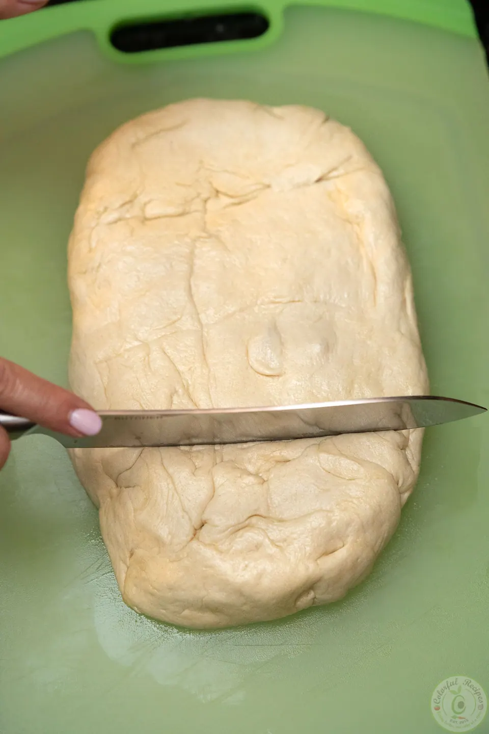 Cutting pizza dough with a knife on a floured cutting board