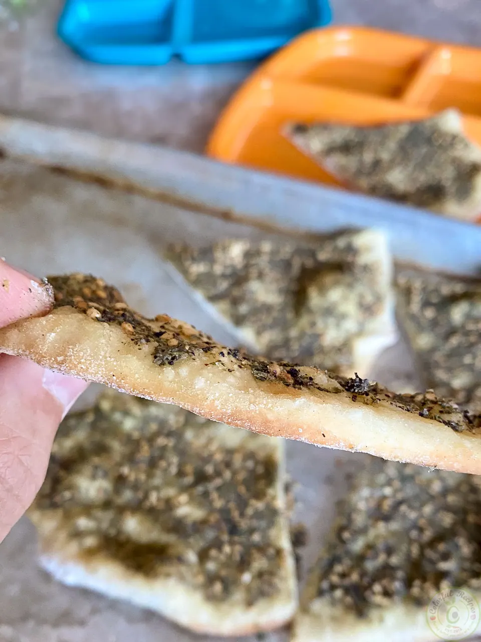 Crispy slice of zaatar mankousheh held up to show its thin crust