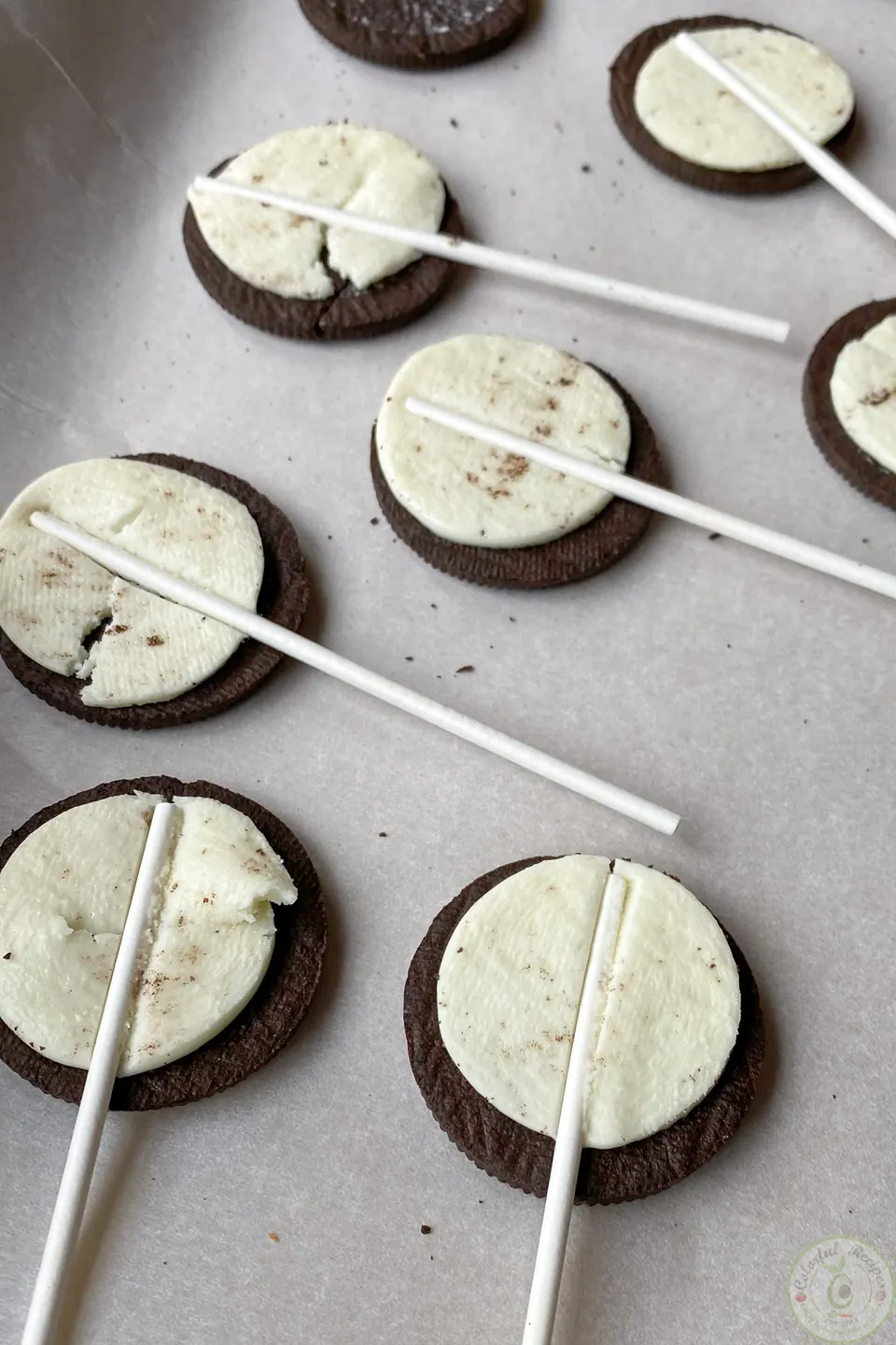 Opened Oreo cookies with lollipop sticks pressed into the filling