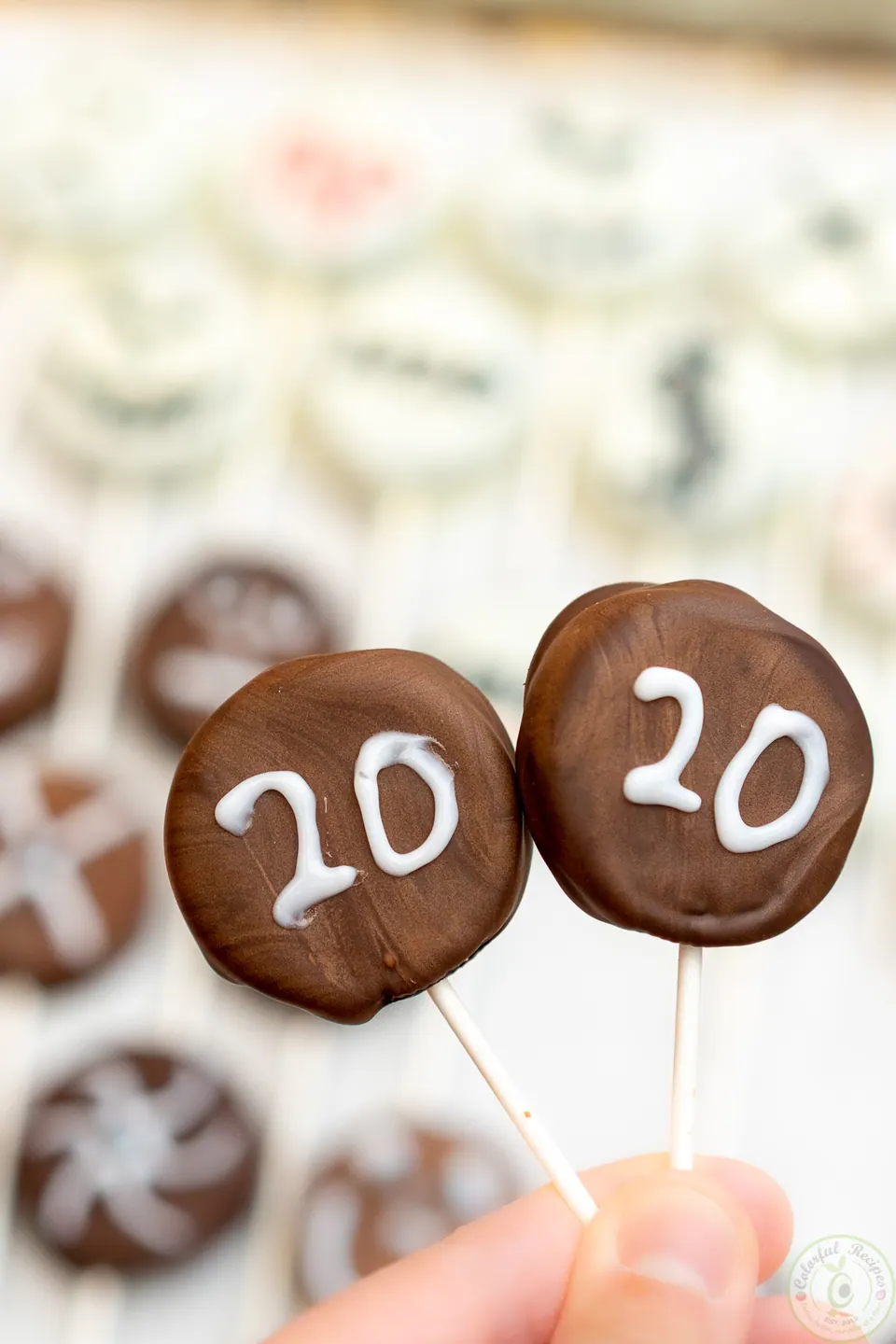 Two chocolate Oreo pops decorated with icing to read 2020