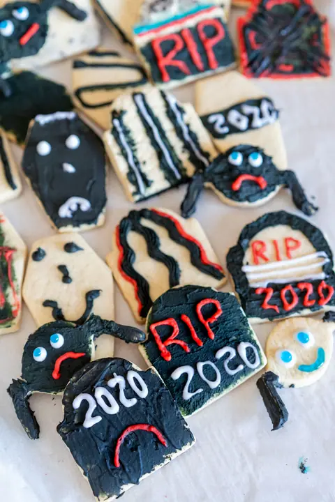 Assortment of decorated Halloween sugar cookies shaped like tombstones, spiders and coffins