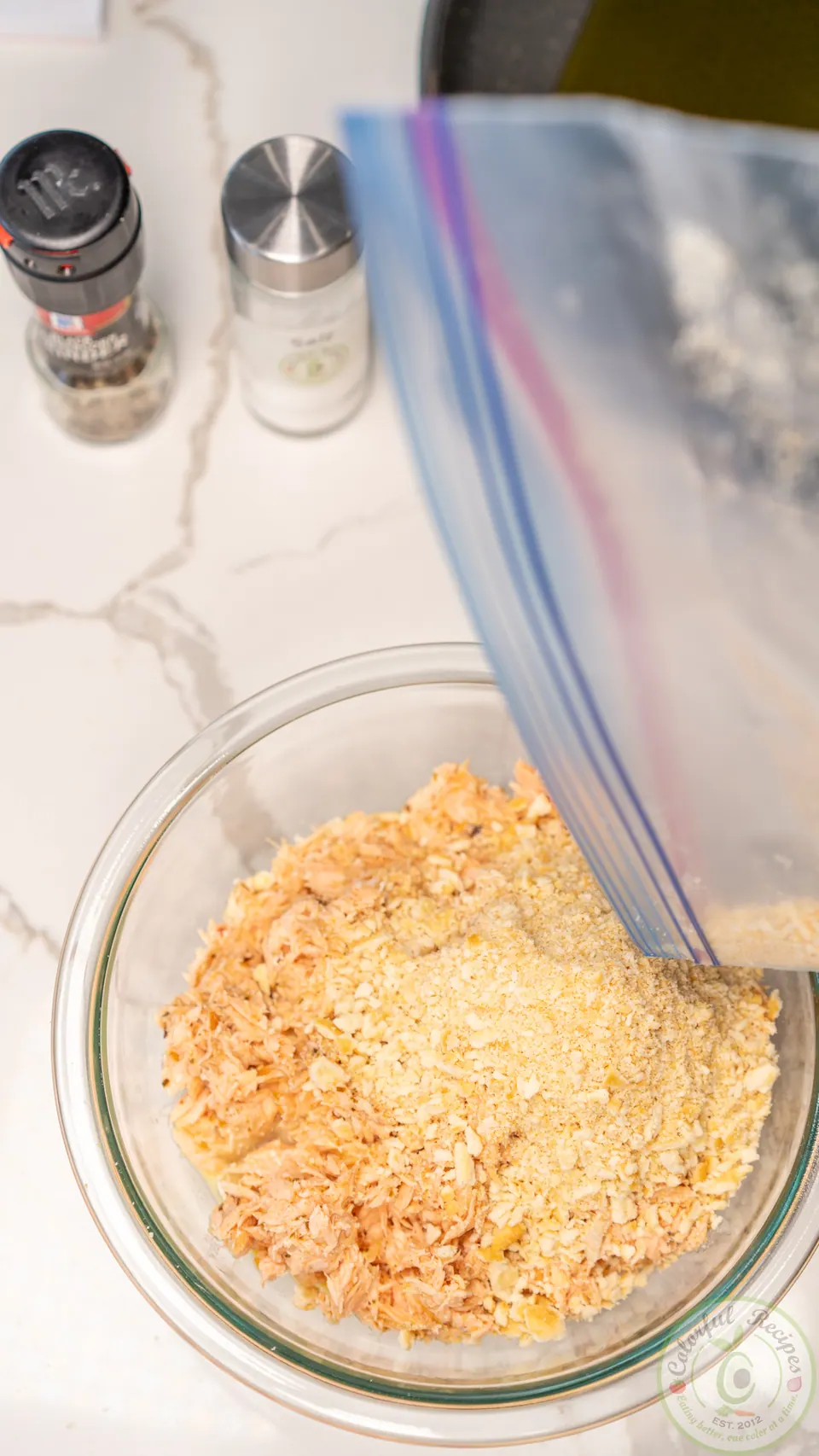 Adding crushed crackers to salmon patty mix