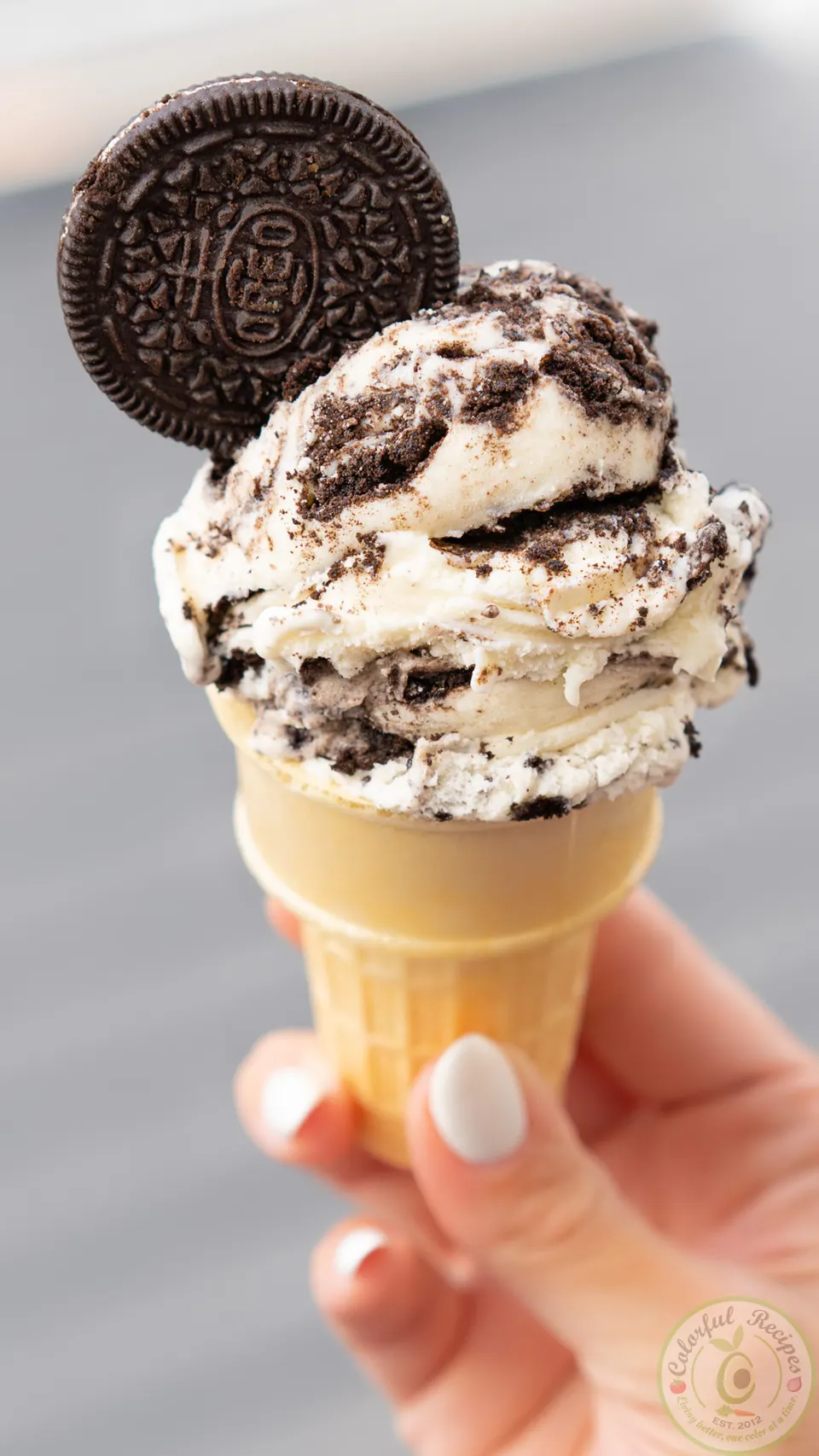Scoop of Oreo vanilla ice cream in a cone with a whole Oreo cookie