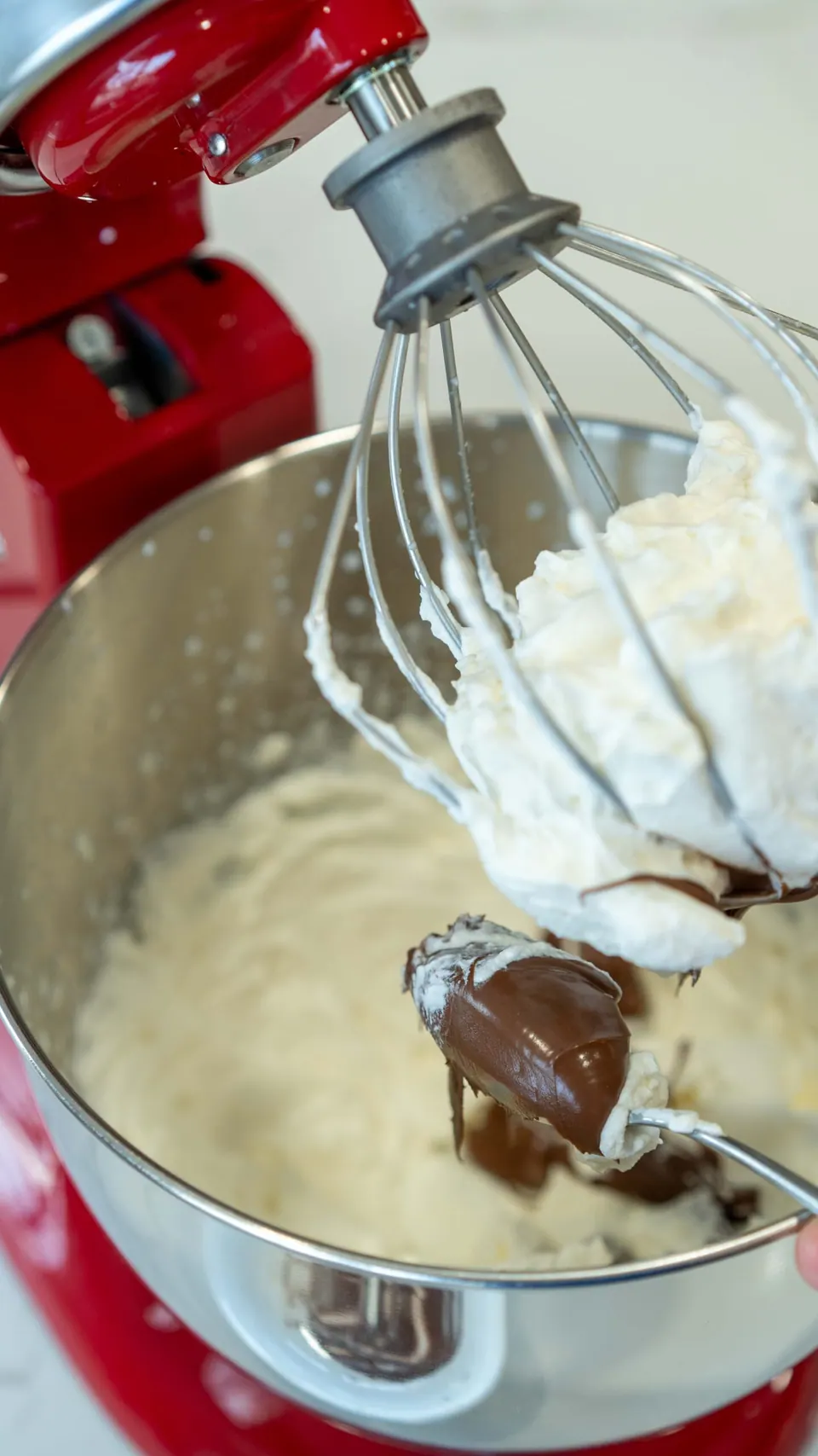 Adding Nutella to whipped cream in a stand mixer for the Yule Log frosting