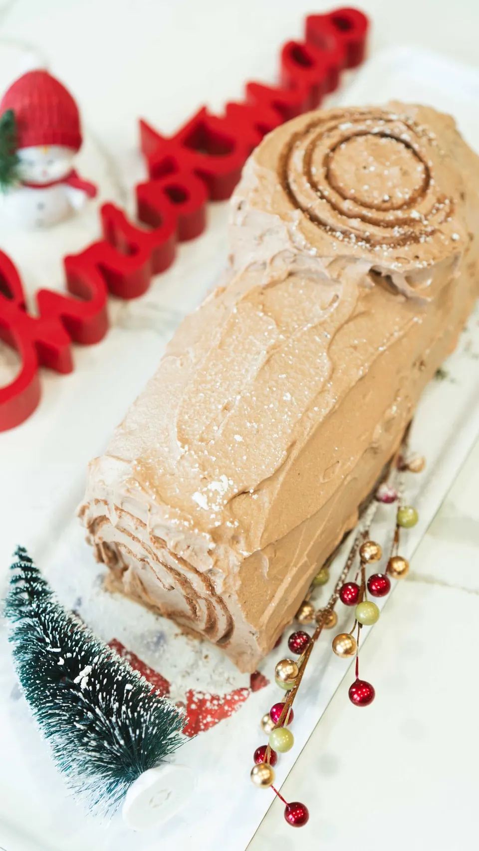 Christmas Yule Log cake (Bûche de Noël) with Nutella whipped cream frosting on a festive holiday table