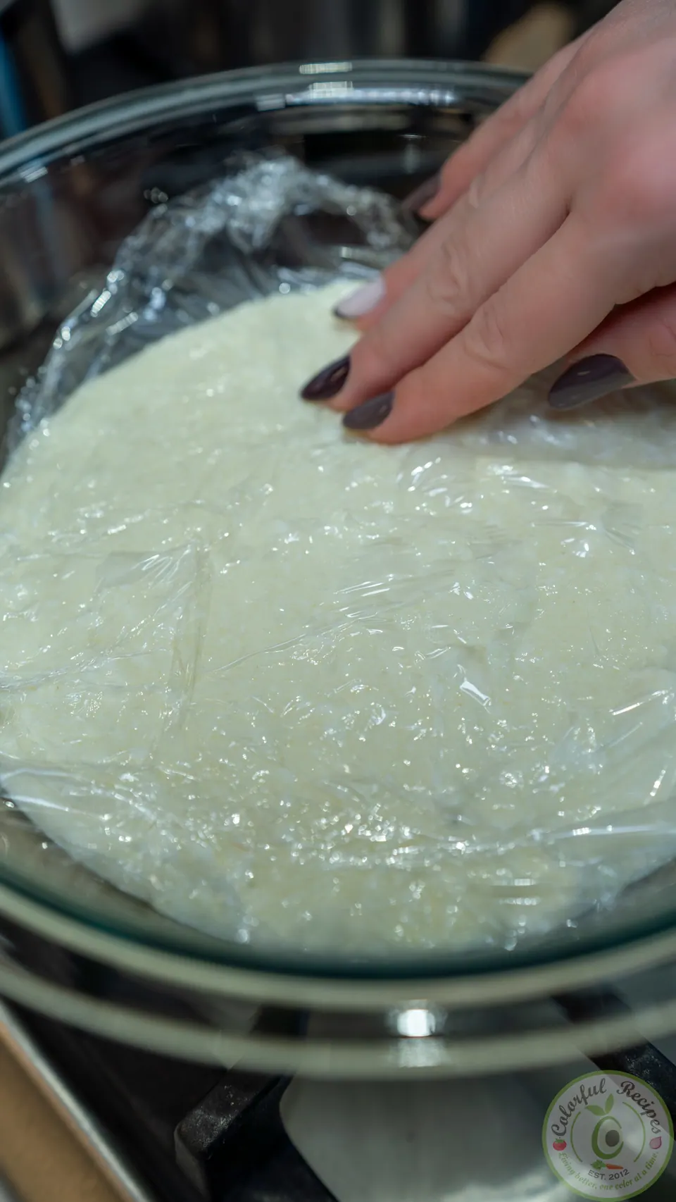 Pressing plastic wrap onto the surface of the ashta filling