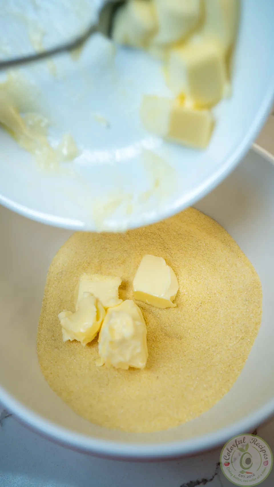 Adding softened butter to the semolina mixture for maamoul dough
