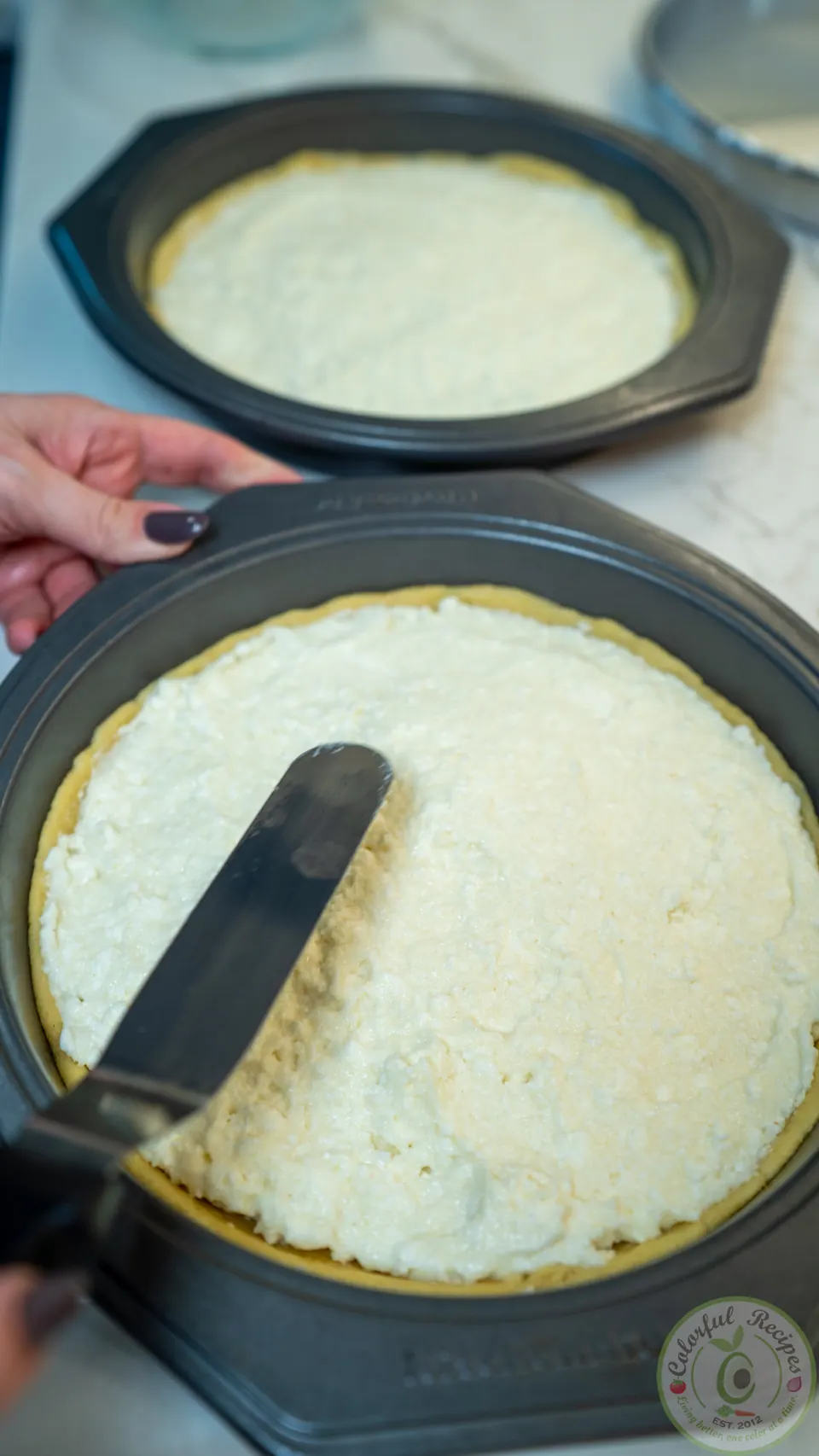 Spreading ashta filling over the dough in a cake pan