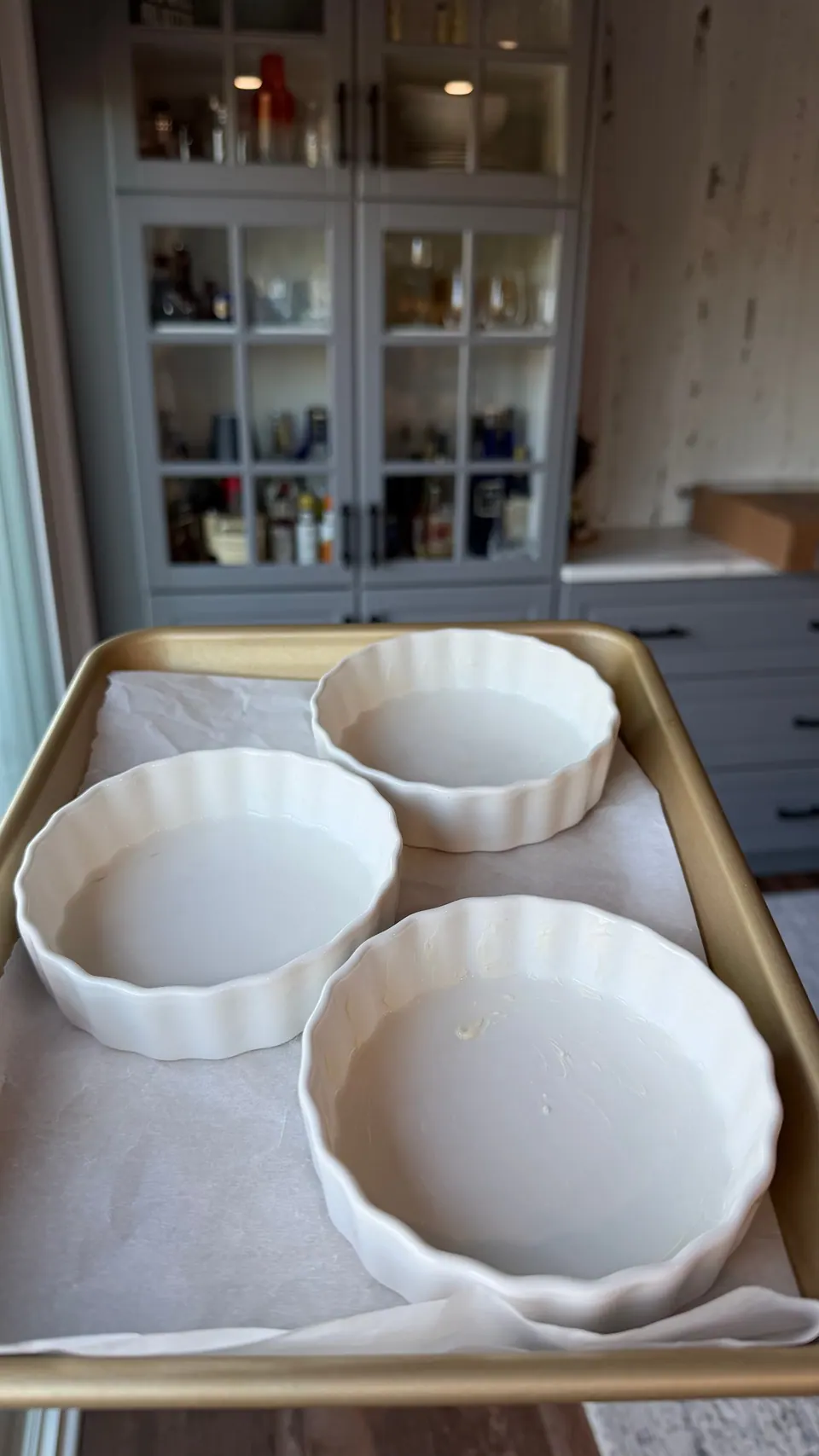 Four greased fluted 4.5-inch ramekins on a parchment-lined baking sheet