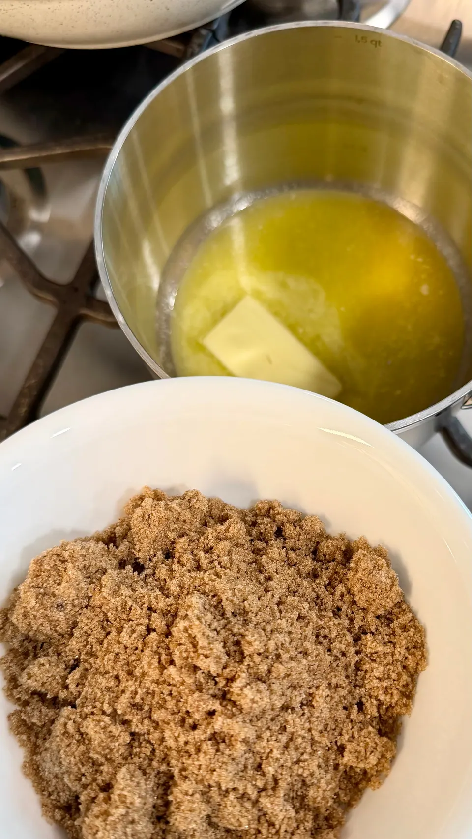 Butter melting in a saucepan next to a bowl of packed dark brown sugar for bourbon caramel